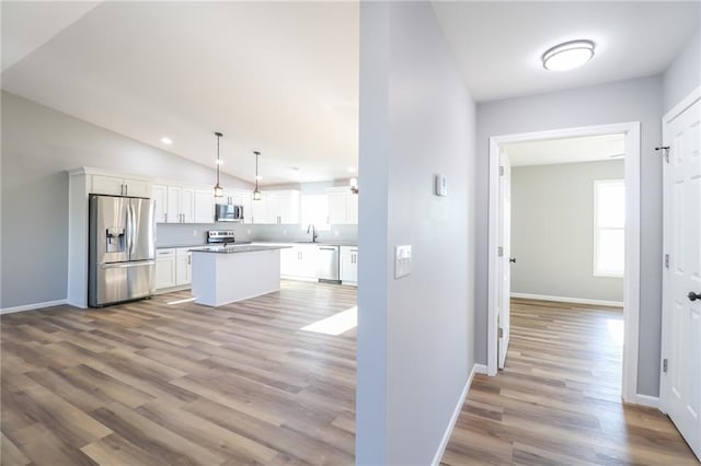 kitchen with pendant lighting, a center island, stainless steel appliances, and white cabinetry