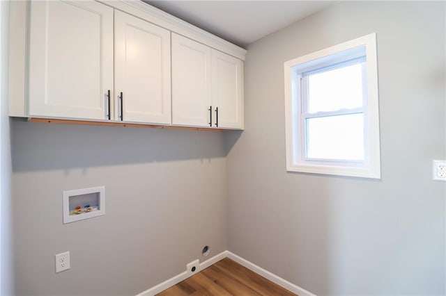 clothes washing area with hardwood / wood-style floors, cabinets, and washer hookup