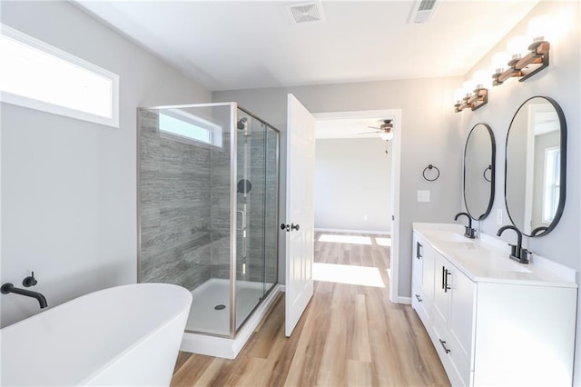 bathroom featuring plus walk in shower, hardwood / wood-style floors, vanity, and ceiling fan