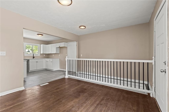 unfurnished living room featuring sink and dark wood-type flooring