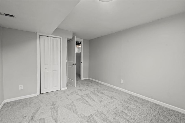 unfurnished bedroom featuring light carpet and a closet