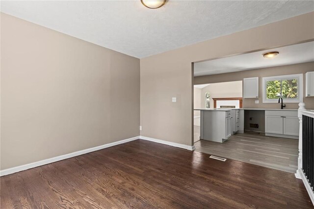 unfurnished living room featuring dark hardwood / wood-style flooring, a textured ceiling, and sink