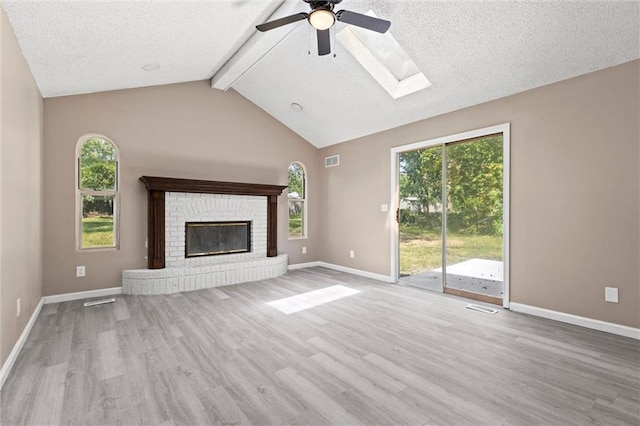 unfurnished living room featuring ceiling fan, light hardwood / wood-style flooring, plenty of natural light, and vaulted ceiling with skylight