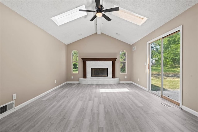 unfurnished living room featuring vaulted ceiling with beams, ceiling fan, a textured ceiling, a fireplace, and light hardwood / wood-style floors