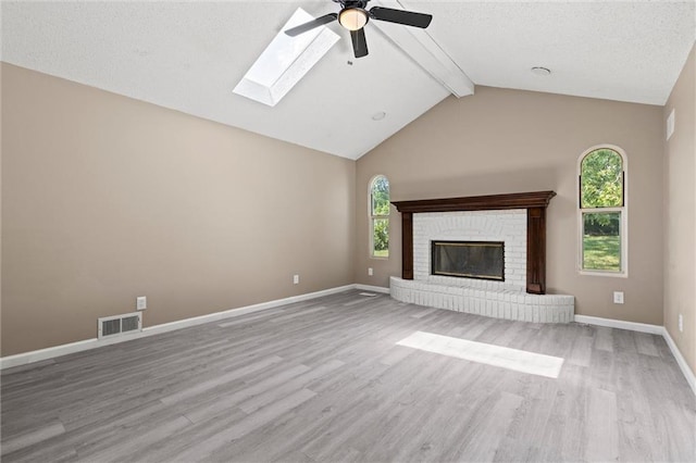 unfurnished living room with light hardwood / wood-style flooring, lofted ceiling with skylight, and a healthy amount of sunlight