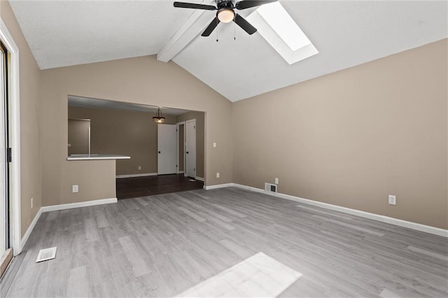 unfurnished living room featuring light hardwood / wood-style floors, lofted ceiling with skylight, and ceiling fan