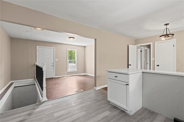 kitchen featuring white cabinetry, pendant lighting, and light hardwood / wood-style floors