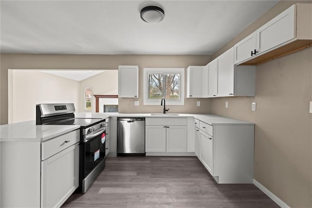 kitchen featuring appliances with stainless steel finishes, sink, white cabinetry, and wood-type flooring