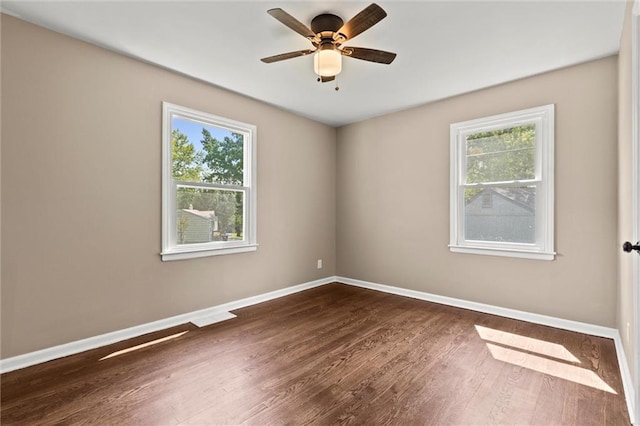 spare room featuring ceiling fan, a healthy amount of sunlight, and dark hardwood / wood-style flooring