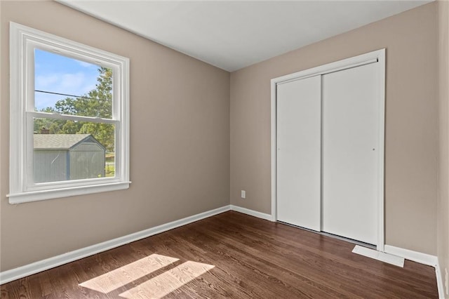 unfurnished bedroom with a closet and dark wood-type flooring