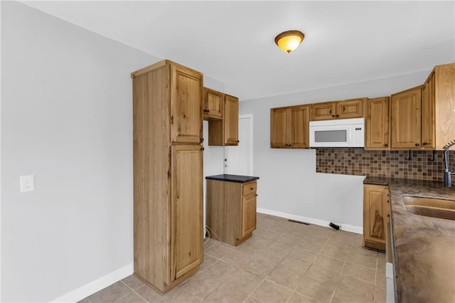 kitchen featuring decorative backsplash, light tile patterned floors, and sink