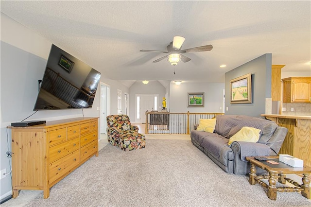 living area with light colored carpet, a textured ceiling, and a ceiling fan