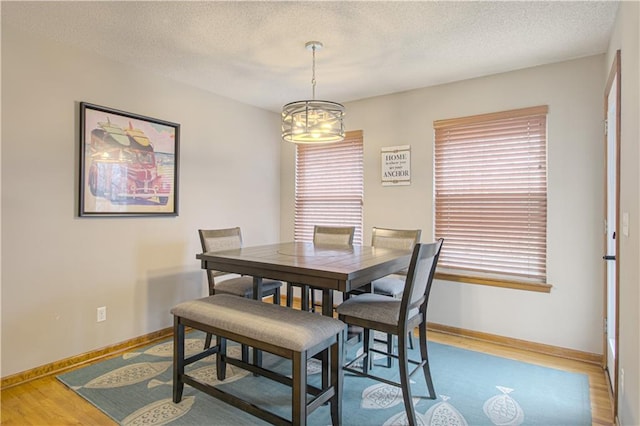 dining room featuring hardwood / wood-style flooring, a textured ceiling, and a notable chandelier