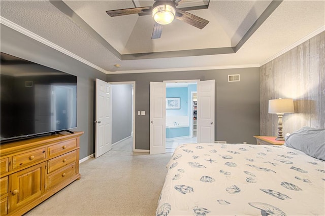 bedroom featuring a raised ceiling, ensuite bathroom, a textured ceiling, and ceiling fan