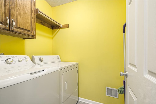 washroom featuring baseboards, cabinet space, visible vents, and washing machine and clothes dryer