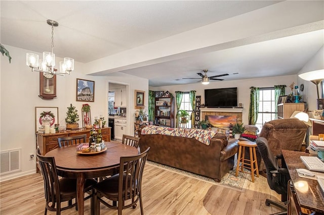 dining area featuring ceiling fan with notable chandelier and light wood-type flooring