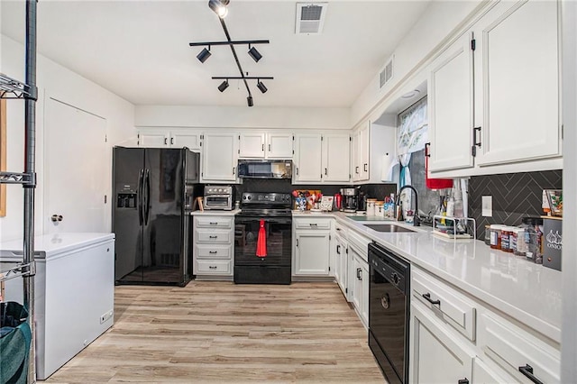 kitchen featuring light wood-type flooring, sink, white cabinetry, and black appliances