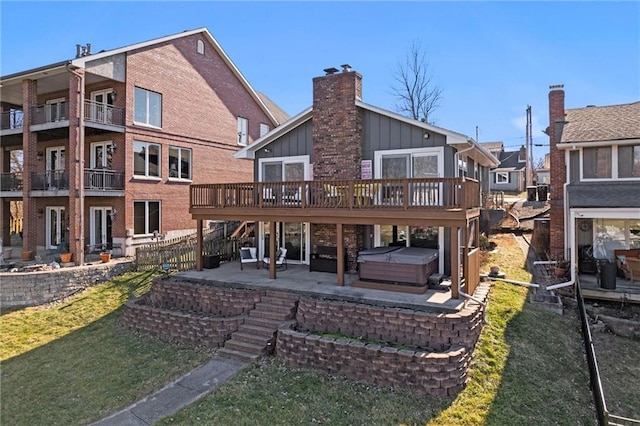 back of property featuring a patio, a hot tub, a deck, a lawn, and board and batten siding