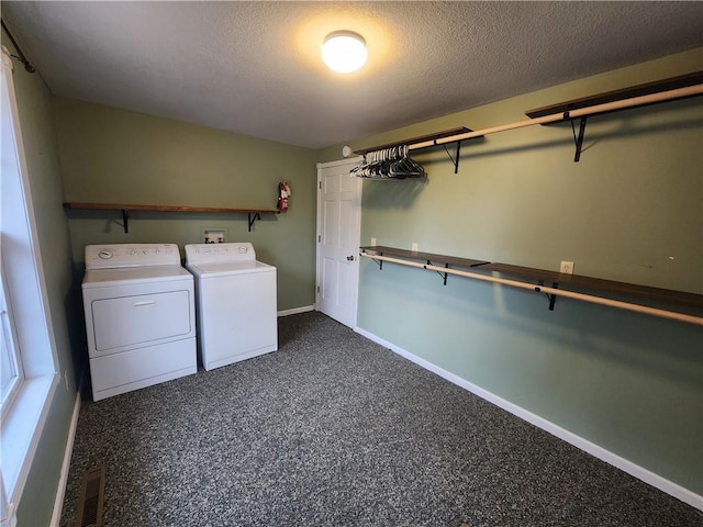 laundry area featuring dark carpet, washing machine and dryer, and a textured ceiling