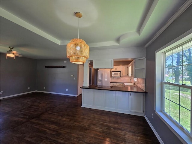 909 N Fulton St, Butler, MO 64730 - kitchen featuring white appliances, dark countertops, a tray ceiling, white cabinetry, and a ceiling fan