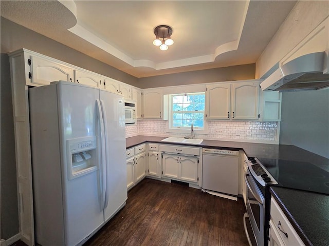 909 N Fulton St, Butler, MO 64730 - kitchen with white appliances, range hood, a raised ceiling, dark wood-style flooring, and white cabinetry