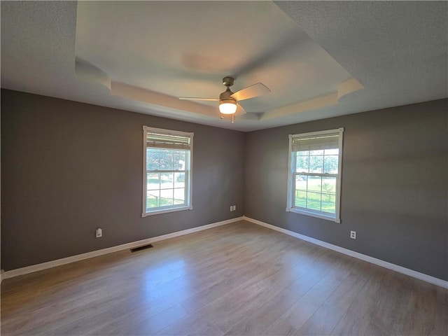 909 N Fulton St, Butler, MO 64730 - spare room with a raised ceiling, plenty of natural light, ceiling fan, and wood finished floors