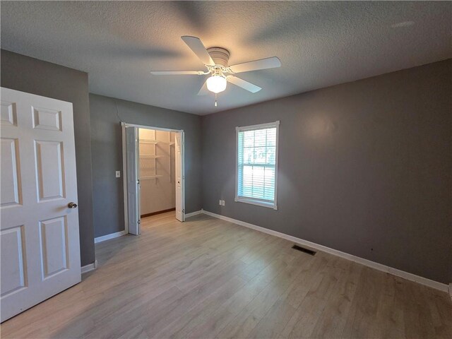 909 N Fulton St, Butler, MO 64730 - unfurnished bedroom with light wood finished floors, a textured ceiling, and a ceiling fan