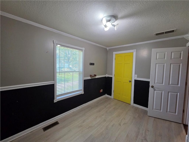 909 N Fulton St, Butler, MO 64730 - unfurnished room featuring light wood-style flooring, a textured ceiling, and crown molding