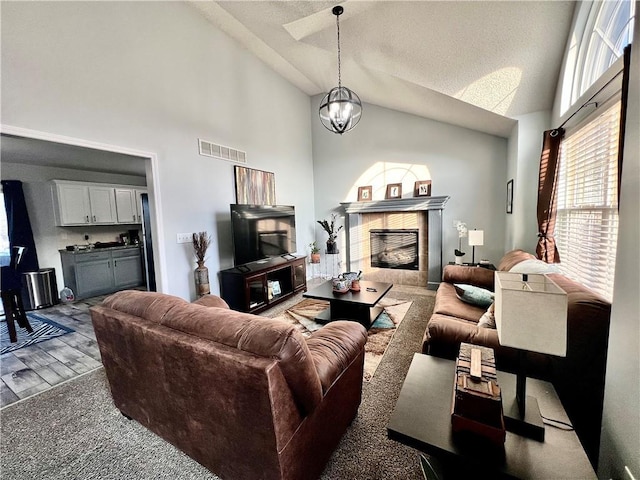 living room featuring lofted ceiling, dark wood-type flooring, a tile fireplace, and an inviting chandelier