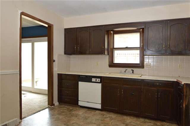 kitchen featuring dark brown cabinetry, white dishwasher, backsplash, and sink