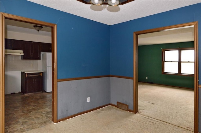 empty room featuring ceiling fan, carpet floors, and a textured ceiling