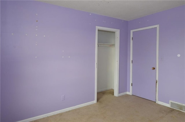 unfurnished bedroom featuring light carpet and a closet