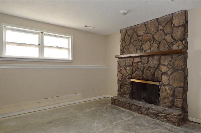 interior space featuring a stone fireplace, a textured ceiling, and concrete floors