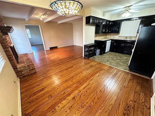 kitchen with beam ceiling, tasteful backsplash, white dishwasher, wood-type flooring, and black refrigerator