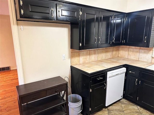 kitchen featuring dishwasher, backsplash, and tile countertops