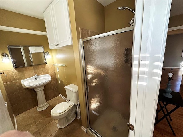 bathroom featuring tile patterned flooring, toilet, tile walls, and walk in shower