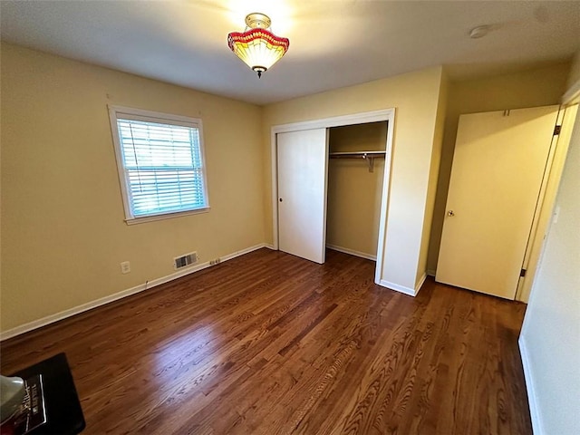 unfurnished bedroom with dark hardwood / wood-style floors and a closet