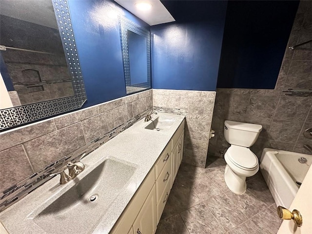 bathroom featuring vanity, a bathtub, tile patterned flooring, toilet, and tile walls