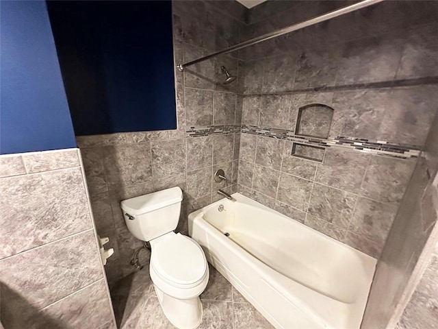 bathroom featuring tiled shower / bath, tile walls, and toilet