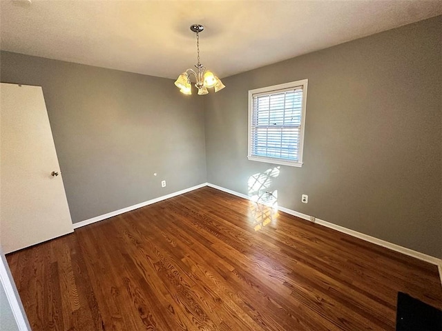 unfurnished room with a notable chandelier and dark hardwood / wood-style floors