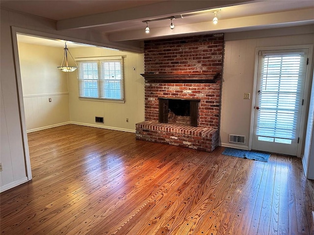 unfurnished living room with a fireplace, wood-type flooring, track lighting, and beamed ceiling