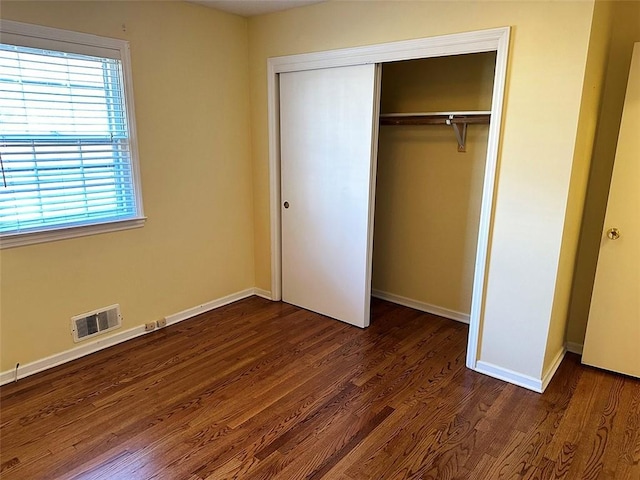 unfurnished bedroom featuring a closet and dark wood-type flooring