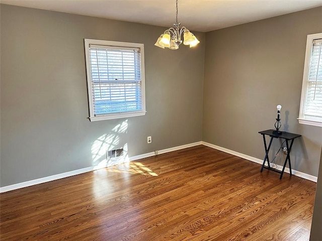 unfurnished room with dark hardwood / wood-style flooring, plenty of natural light, and a chandelier