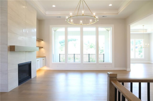 21513 W 80th Ter, Shawnee, KS 66220 - unfurnished living room with a chandelier, light wood finished floors, a tray ceiling, crown molding, and a tile fireplace