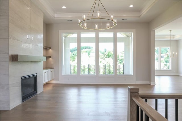 21513 W 80th Ter, Shawnee, KS 66220 - unfurnished living room featuring a raised ceiling, a chandelier, wood finished floors, crown molding, and plenty of natural light