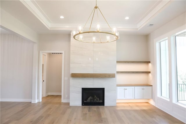 21513 W 80th Ter, Shawnee, KS 66220 - unfurnished living room featuring a raised ceiling, light wood-style floors, a chandelier, crown molding, and a large fireplace