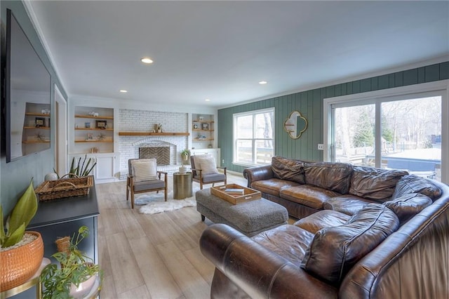 living room featuring a fireplace, light hardwood / wood-style floors, and built in shelves