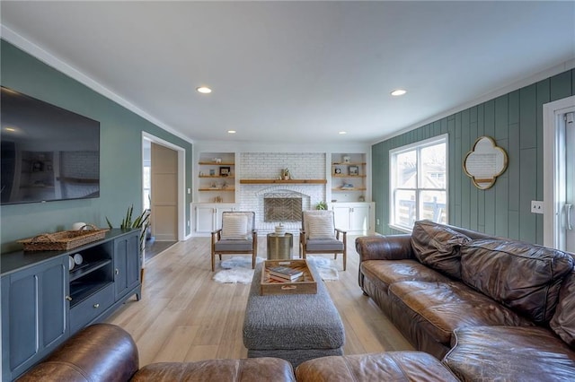 living room featuring ornamental molding, a fireplace, built in features, and light wood-type flooring