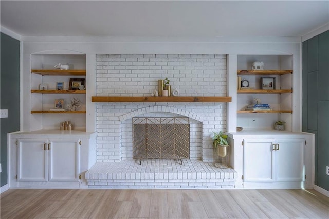 unfurnished living room featuring a fireplace, built in features, and light hardwood / wood-style floors