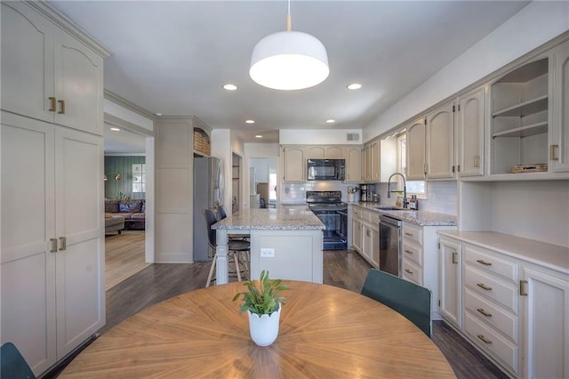 kitchen featuring sink, light stone counters, dark hardwood / wood-style flooring, a kitchen island, and black appliances